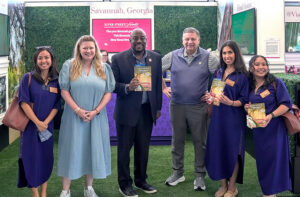 Visit Savannah is bringing the sights, sounds, flavors, and hospitality of Savannah directly to travelers at Chicago’s O’Hare International Airport through a four-week, multi-sensory brand activation in Terminal 3, which runs through May 24. Shown here with Savannah Brand Ambassadors, wearing navy Emily McCarthy dresses, are Angela Westerfield (second from left), Chief Marketing Officer, Visit Savannah; Savannah Mayor Van Johnson (center left); and Visit Savannah President & CEO, Joseph Marinelli (center right), President & CEO, Visit Savannah.